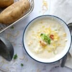 baked potato soup in a bowl with green onions cheese and bacon bits