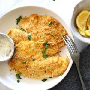 parmesan crusted air fried tilapia with tartar sauce and lemon wedges