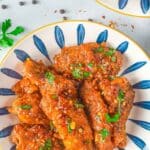 bowl of sweet thai chili chicken wings with red pepper flakes scattered about