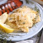 silky creamy sauce over large ravioli next to a lobster tail