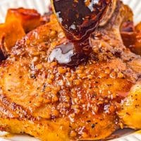 spoon pouring thick, sticky bourbon glaze on top of pork chop