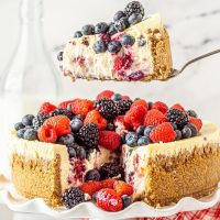 triple berry cheesecake slice with blueberries, strawberries, and blackberries