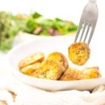 fork with a diced roasted potato and salad in the background