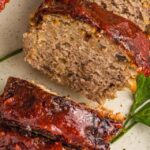 loaf of turkey meatloaf with a vibrant red glaze next to parsley garnish