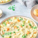 chicken pot pie soup in a bowl with garnish and biscuits