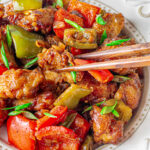 black pepper chicken with green and red bell peppers and chopsticks