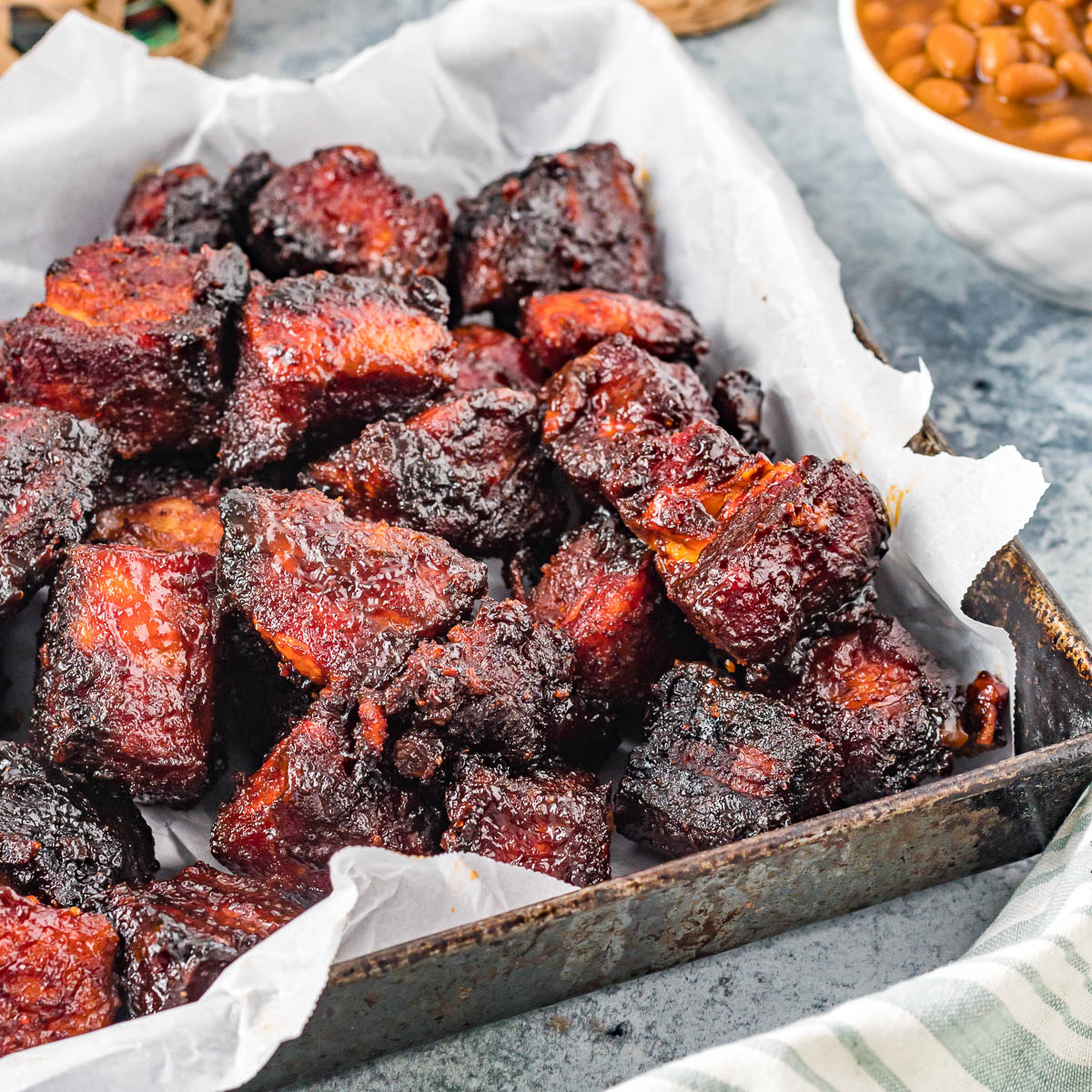 grilled burnt ends in a pan next to baked beans